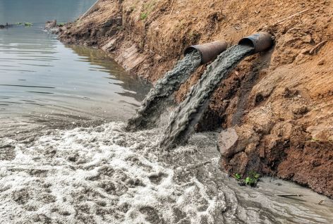 Polluted brown water flowing into river