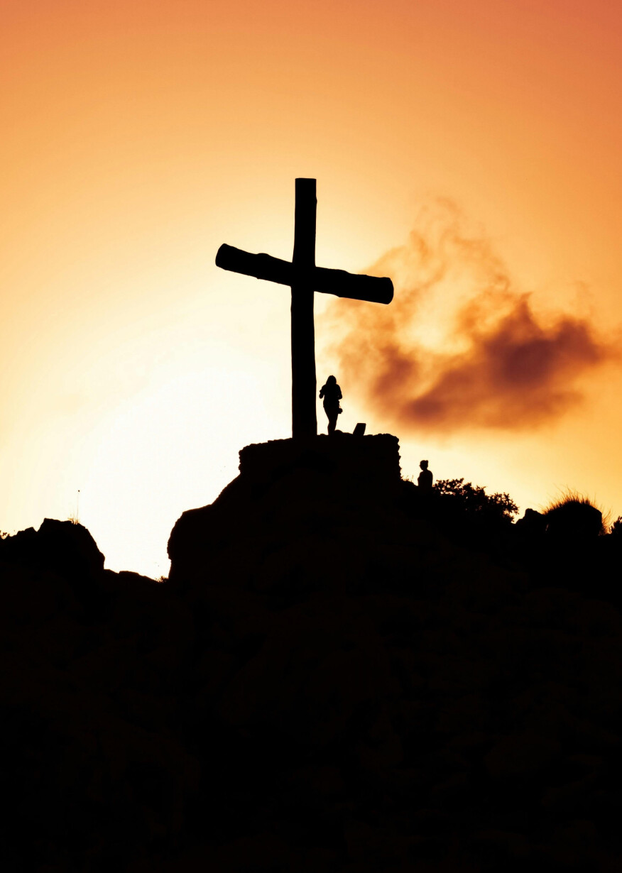 Cross silhouette atop hill