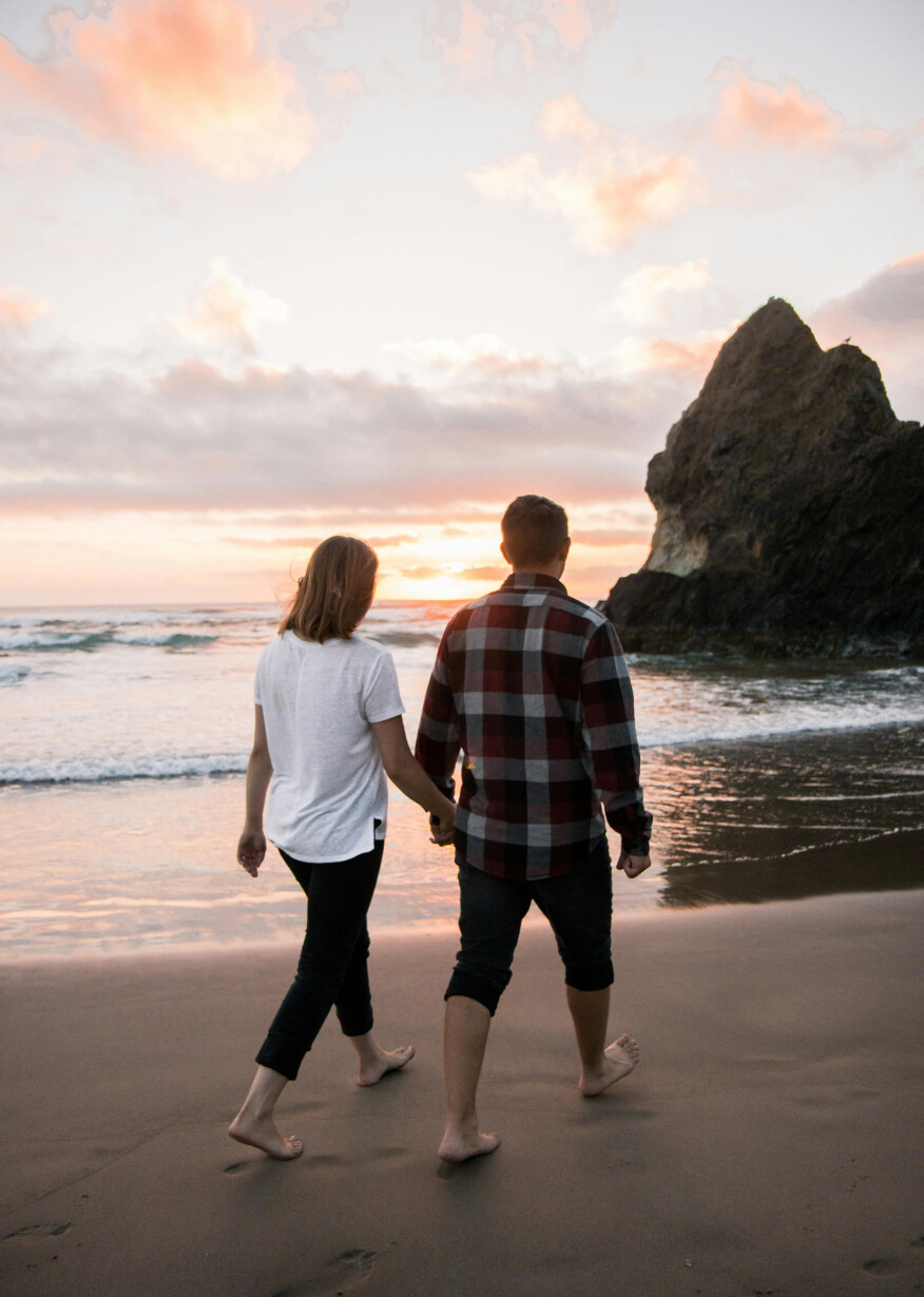 Couple holds hands on sandy beach