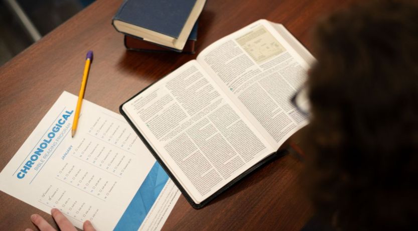 Man reading Bible outdoors on bench