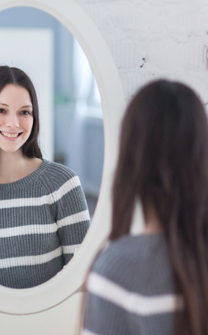 Woman smiling at mirror reflection