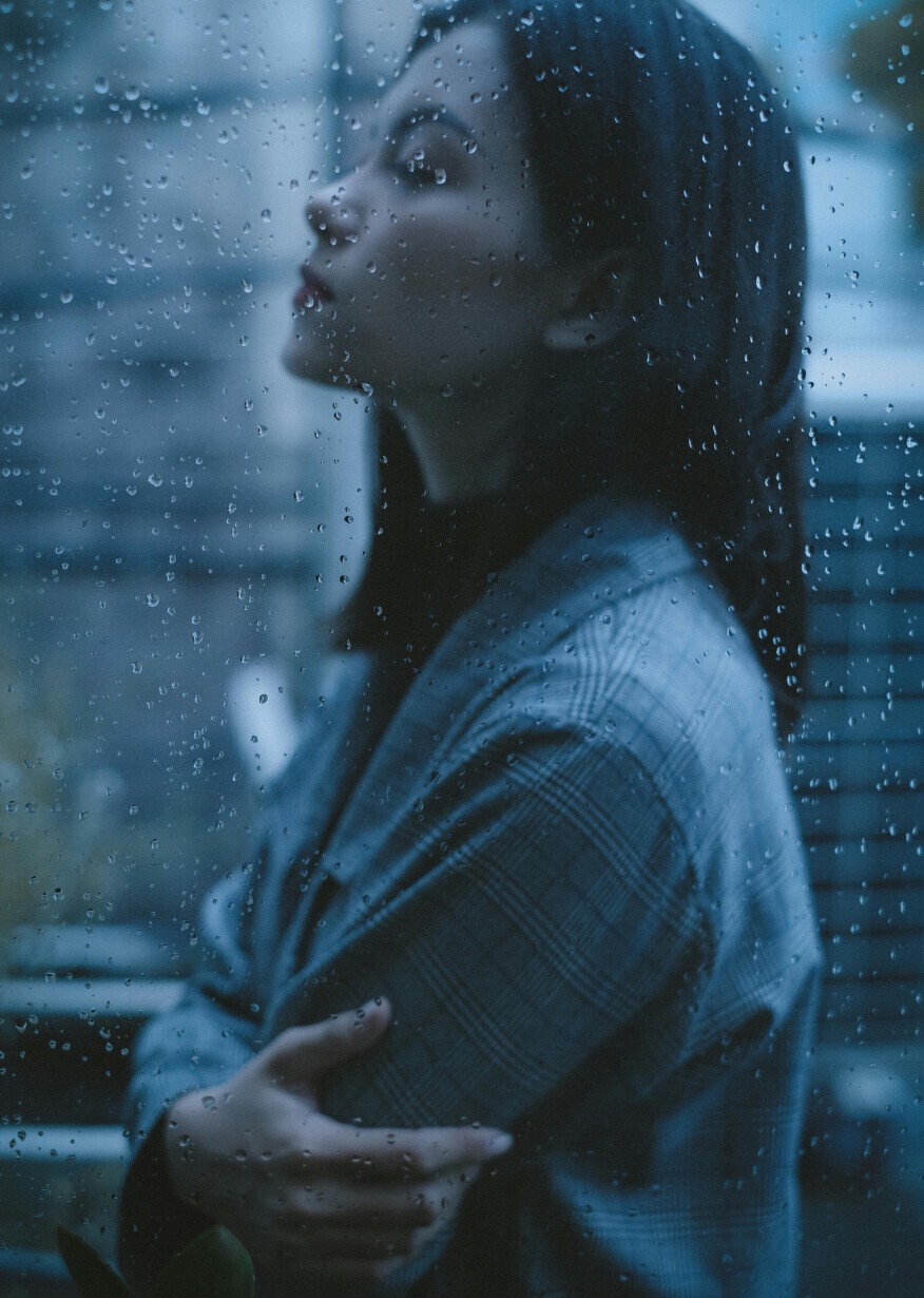 Woman gazes through rainy window