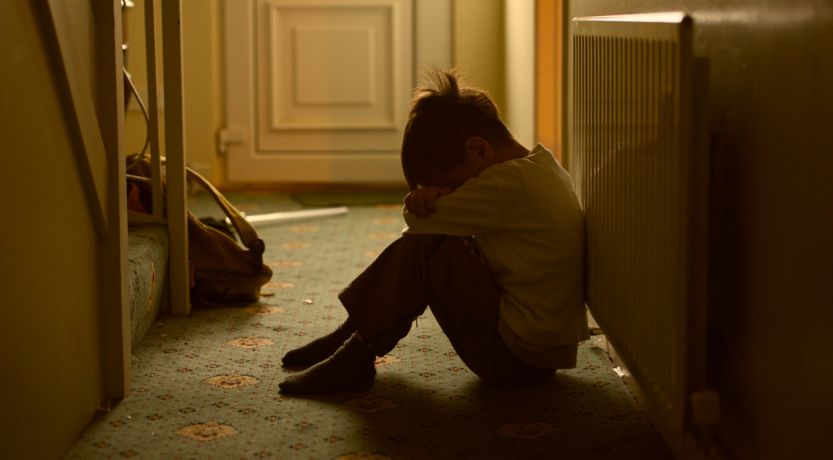 Child sitting alone on floor sadly