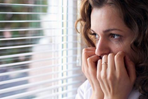 Woman gazes through window fearfully