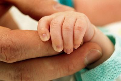 Baby holding adult's finger