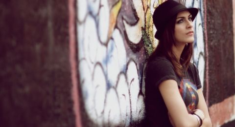 Woman in hat against graffiti wall