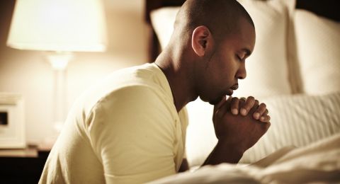 Man kneeling in prayer outdoors