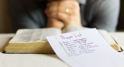 Person praying with Bible and notes