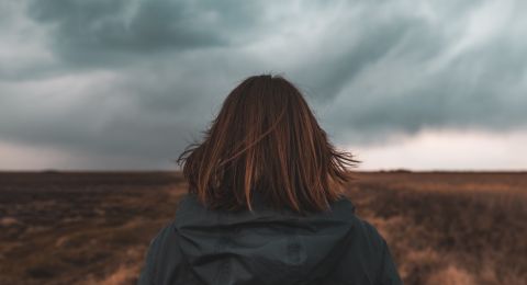 Woman praying in stormy field