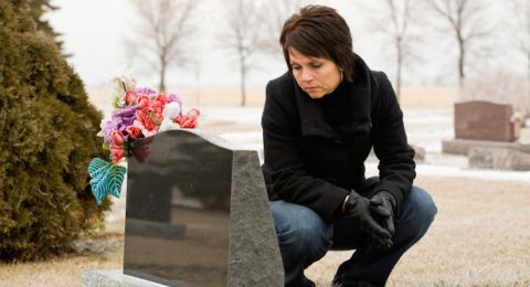 Woman kneeling at gravestone