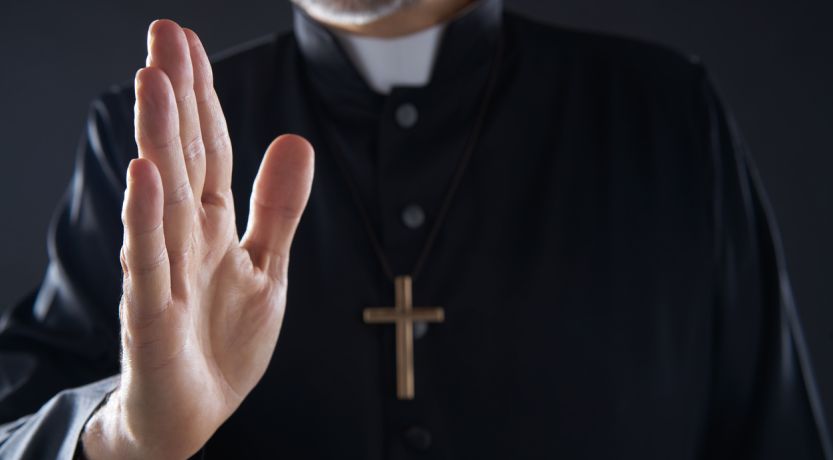 Catholic priest gesturing in blessing pose