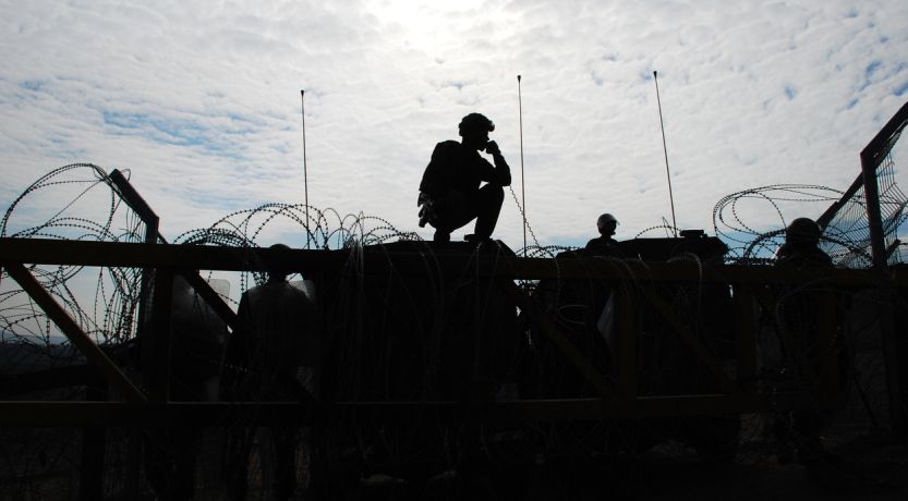 Soldier climbing barbed wire barrier