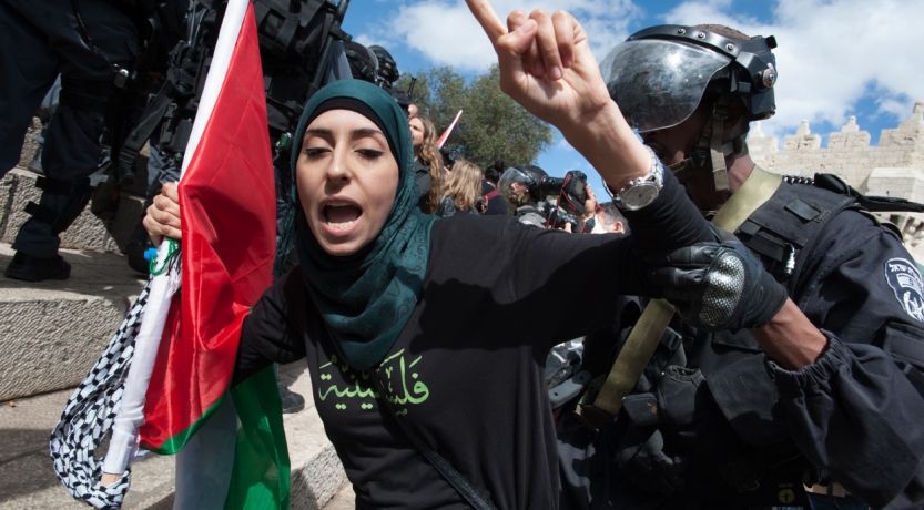 Hijabi woman holds Palestinian flag