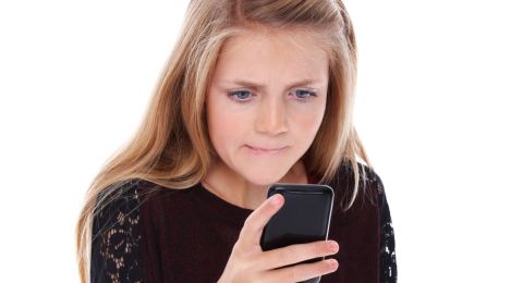 Girl staring at phone, looking concerned