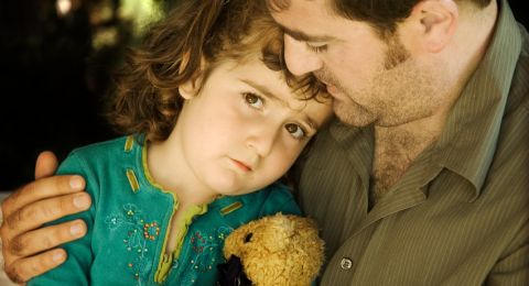 Man comforts crying girl with teddy