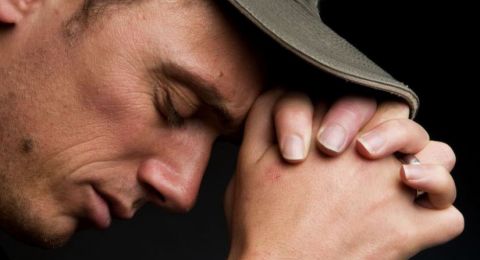 Man praying with hat bowed down