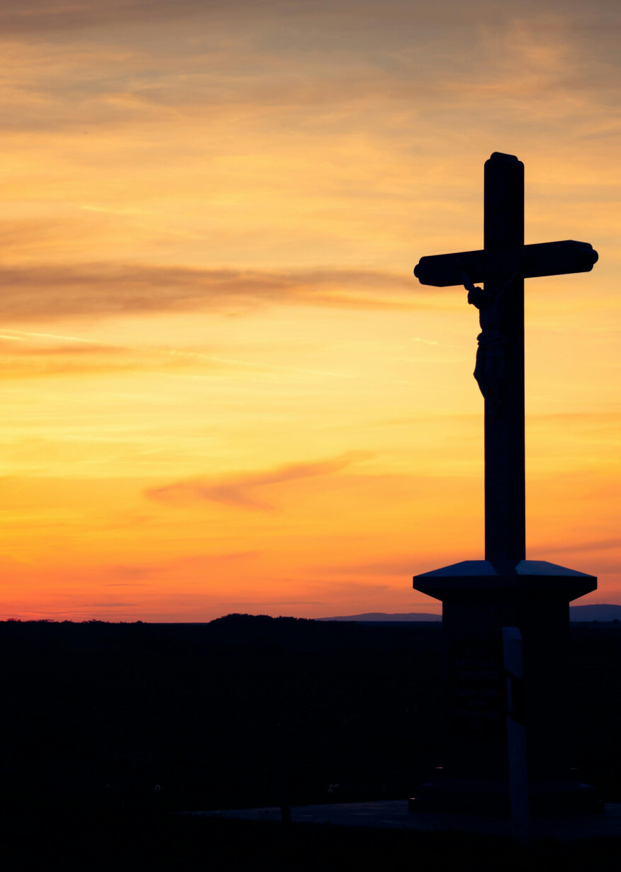 Cross silhouette at dawn sky